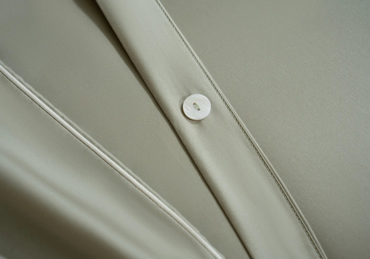 Détail du linge de lit en TENCEL™ Lyocell Maison CÉTOILE avec finition soignée et bouton nacré, illustrant la douceur et l'élégance de la matière.