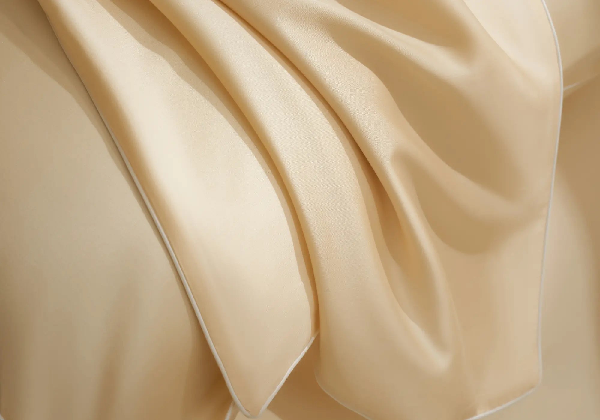 Gros plan sur le linge de lit Ivoire d'Aube en TENCEL™ Lyocell Maison CÉTOILE, mettant en valeur le drapé fluide et le toucher soyeux de la matière.