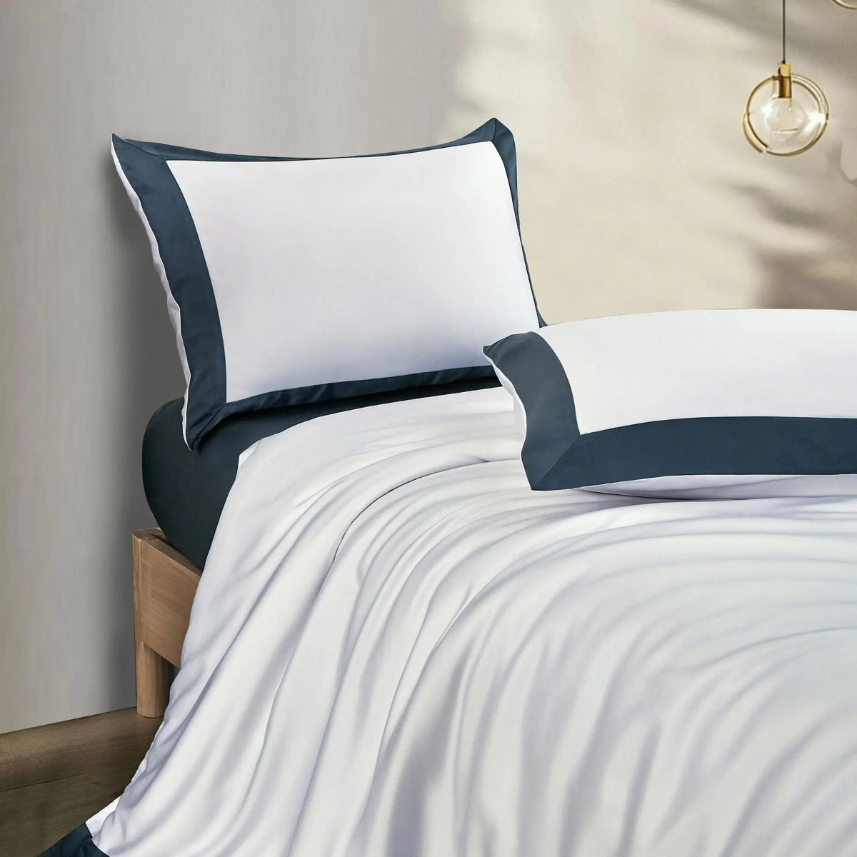 Housse de couette et oreillers blancs en TENCEL™ Lyocell, soulignés d'un élégant liseré bleu nuit.
