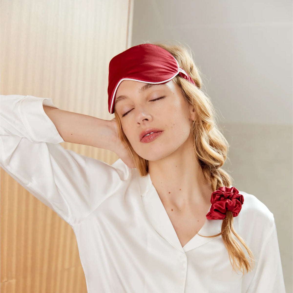 Femme portant le masque de nuit et le chouchou en soie rouge du Pack Silence & Soin Maison CÉTOILE, vêtue d'un pyjama blanc.