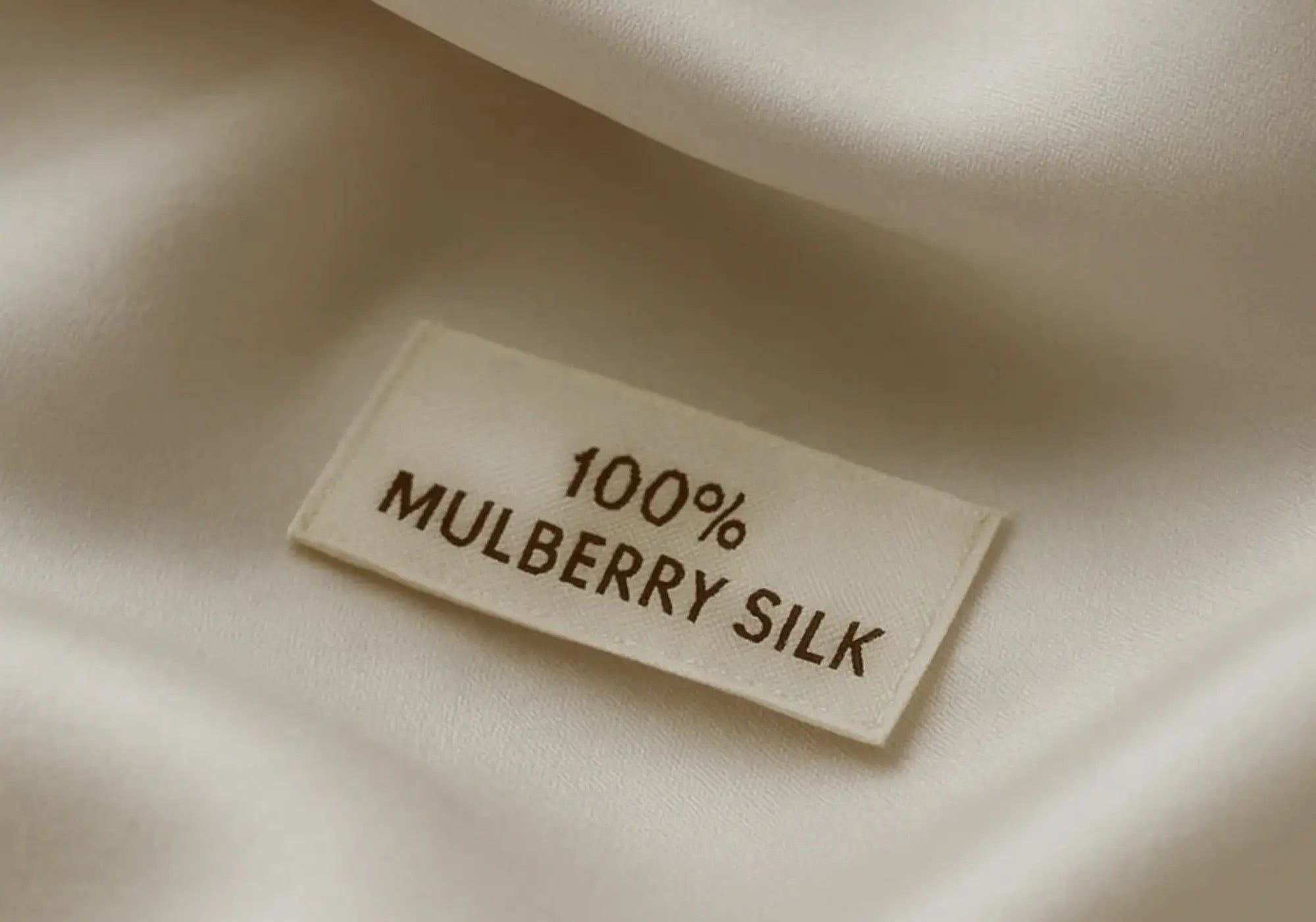 Détail d'une étiquette 100 % soie de mûrier sur linge de lit en soie blanche Maison CÉTOILE