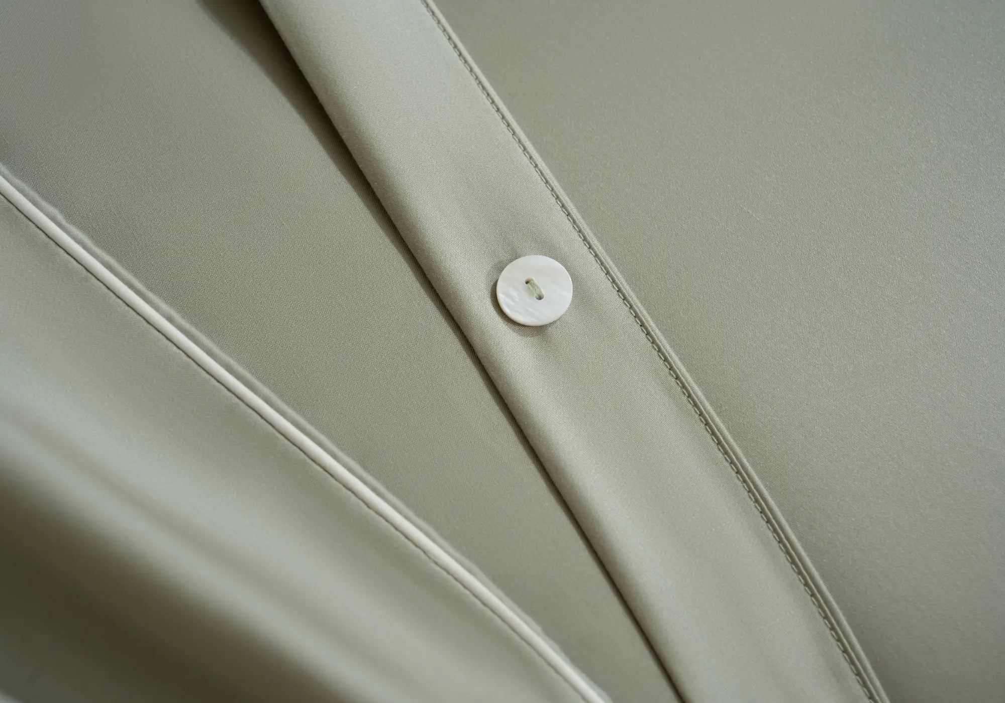 Détail du linge de lit en TENCEL™ Lyocell Maison CÉTOILE avec finition soignée et bouton nacré, illustrant la douceur et l'élégance de la matière.