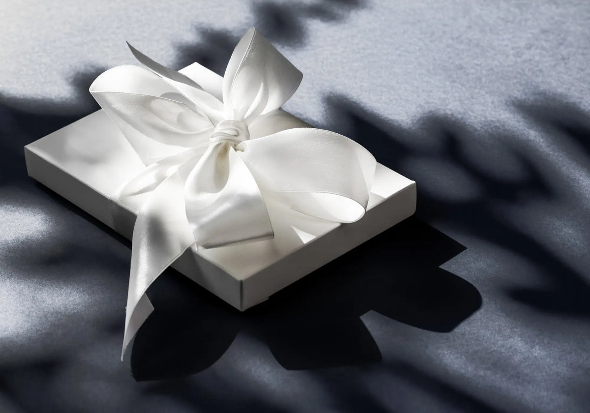 Coffret cadeau élégant avec ruban de satin ivoire sur fond bleu gris