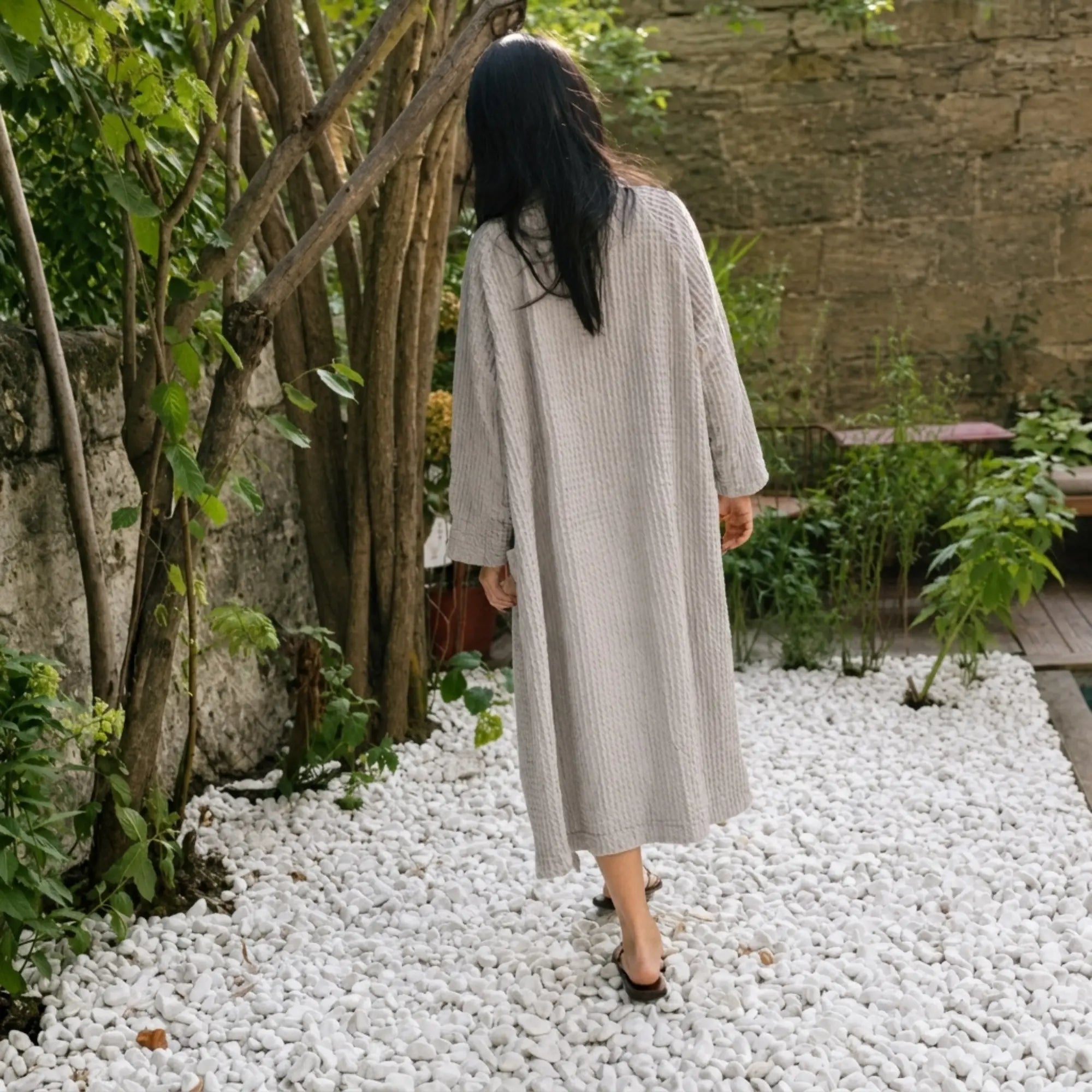 Femme portant le peignoir Waffle en coton gaufré Gris Perle dans un jardin